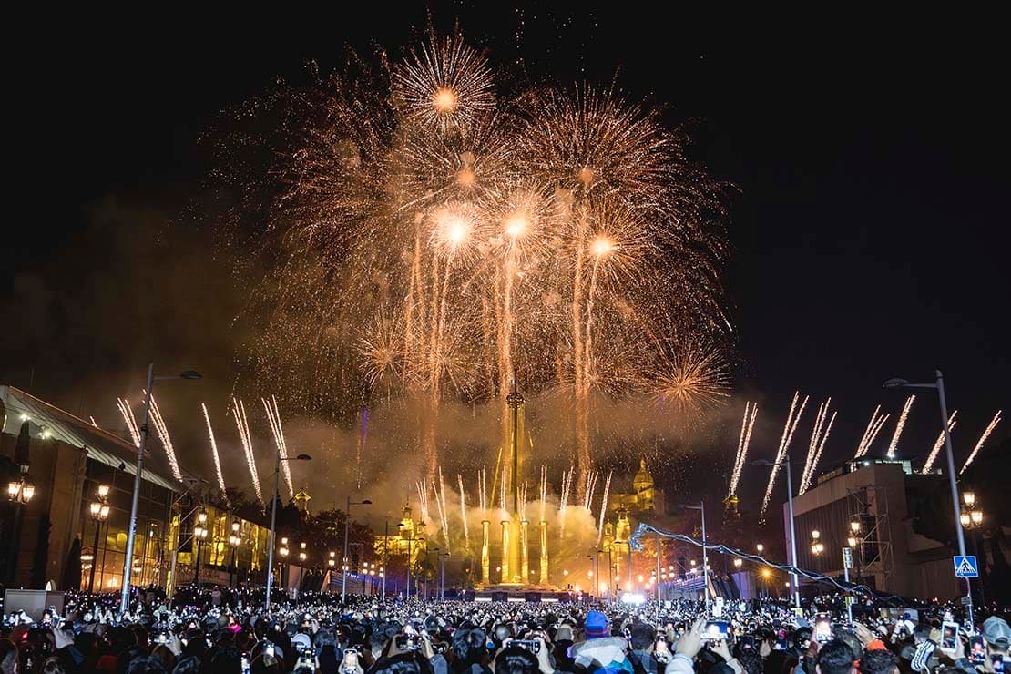 Spectacular New Year’s Eve fireworks display at Montjuïc’s Magic Fountain in Barcelona, with a large crowd celebrating.