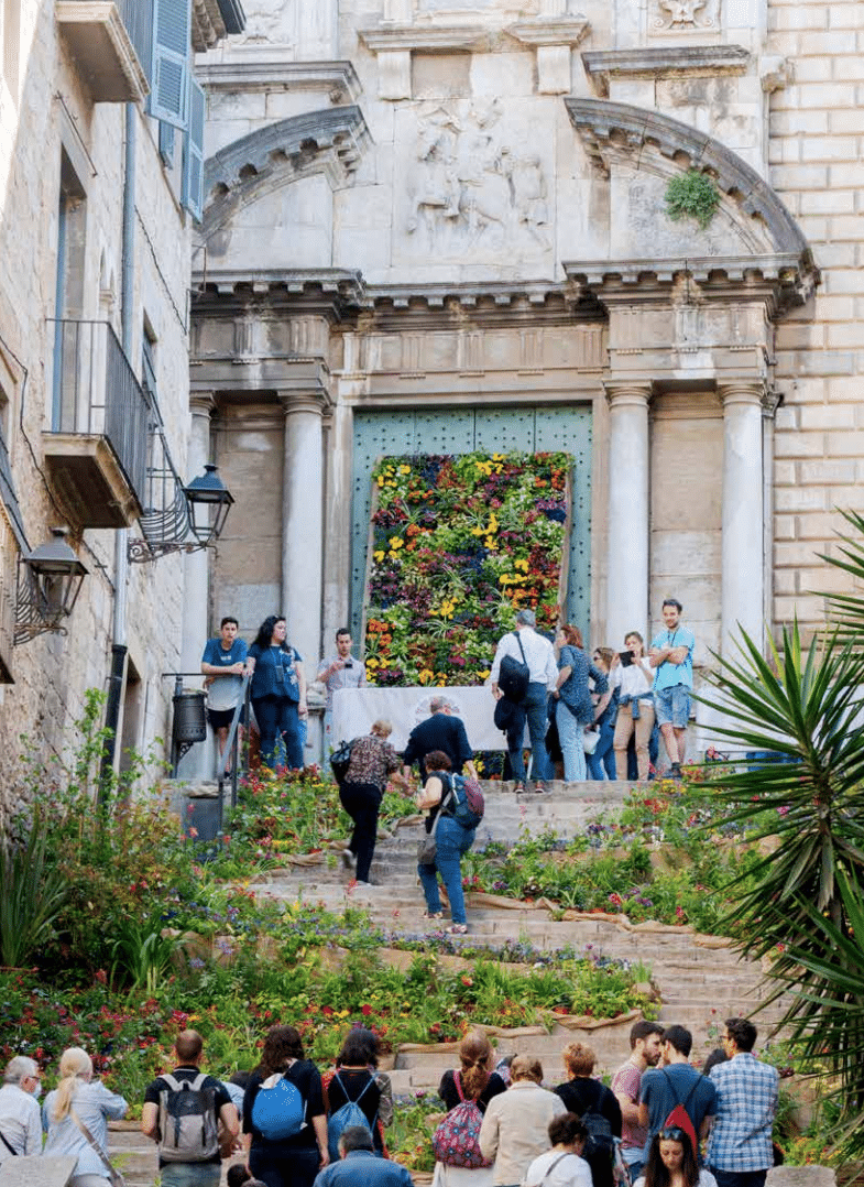 Archway in Girona’s old town decorated with spring flowers and historic stone buildings