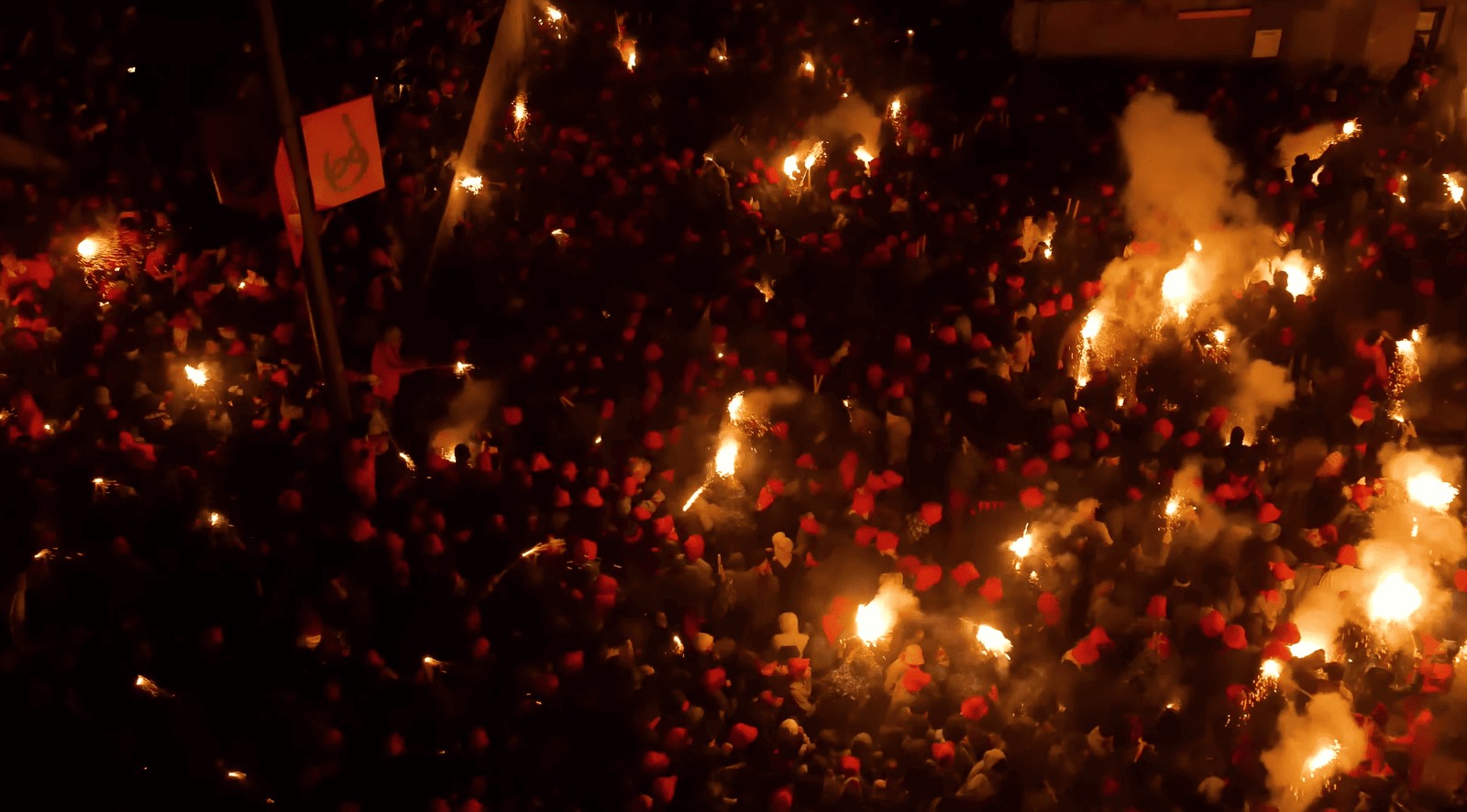 La Patum crowd illuminated by firework flares at night