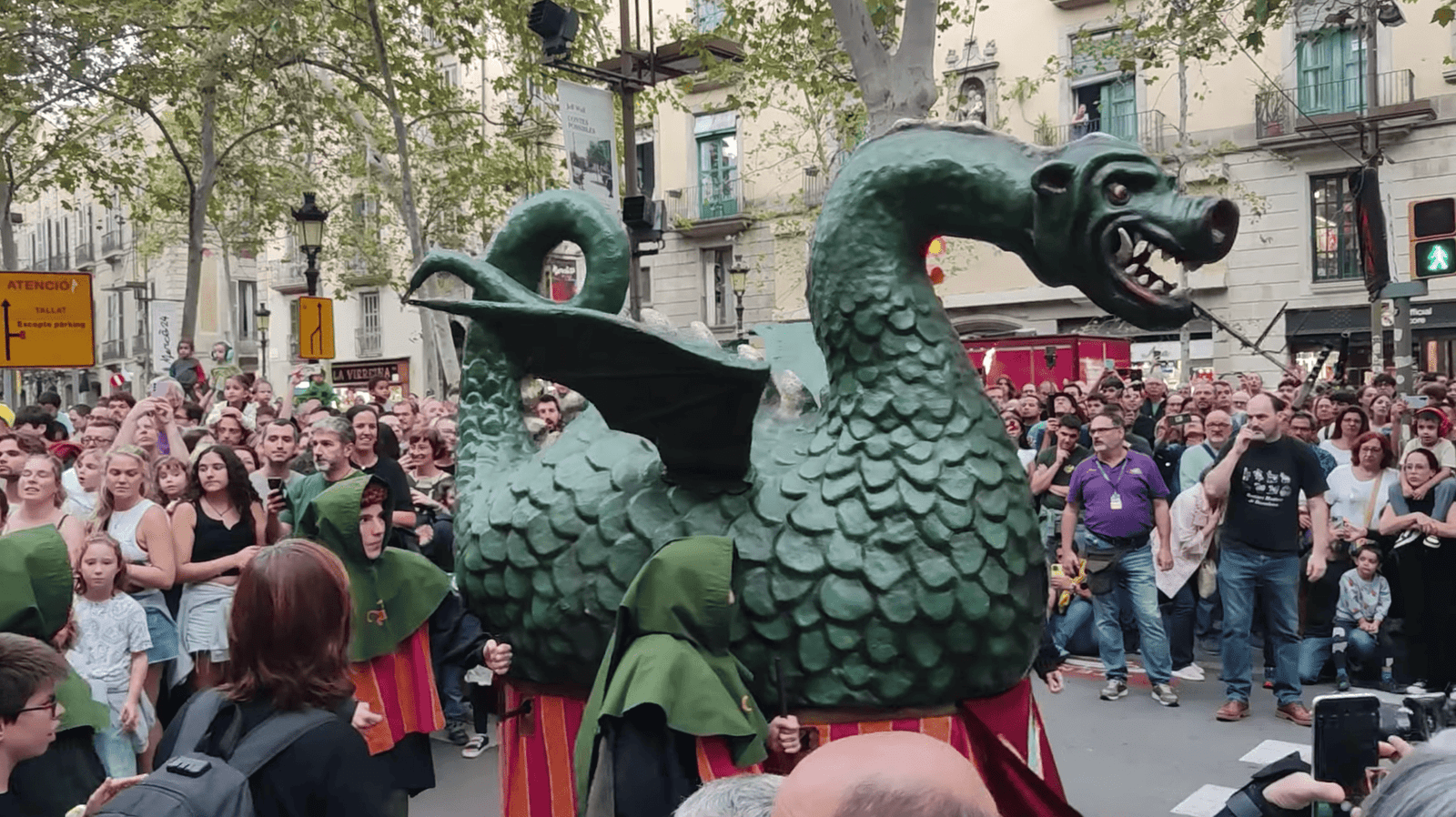 A green multi-headed dragon parades through La Rambla surrounded by spectators during La Mercè.
