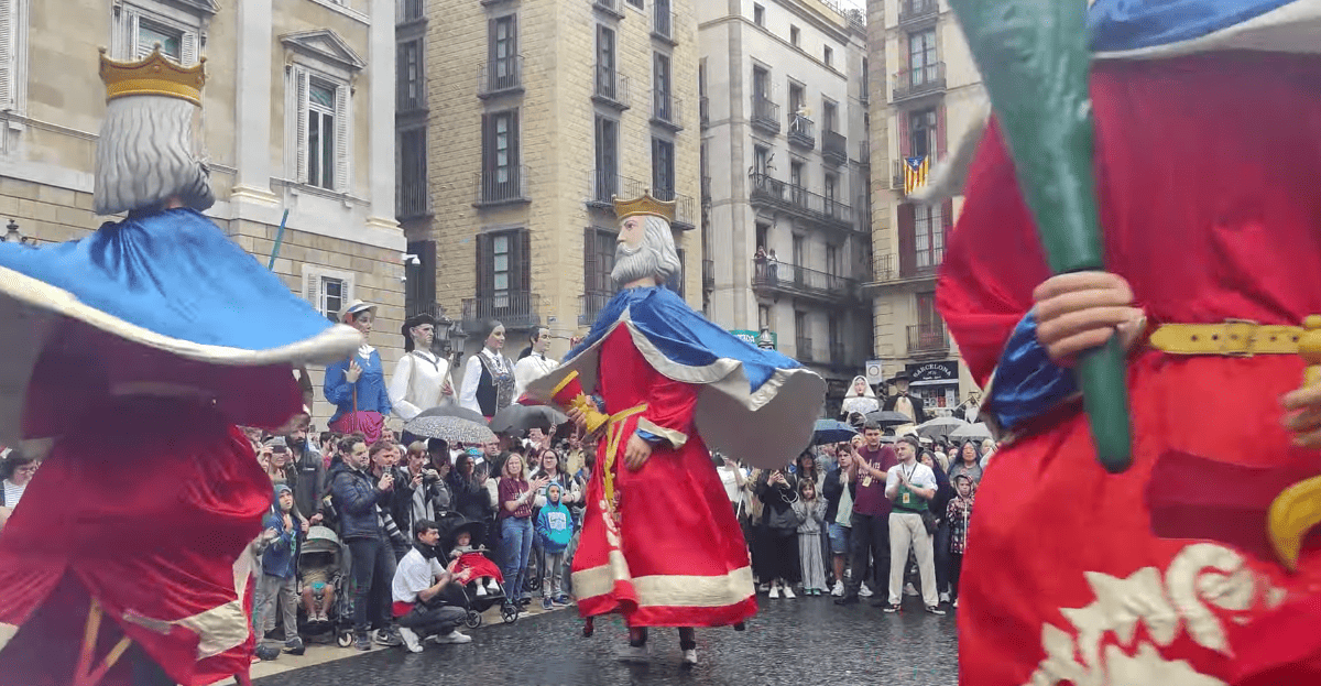 Two capgrossos (big-headed dwarfs) dancing in front of a crowd during La Mercè in the Gothic Quarter.