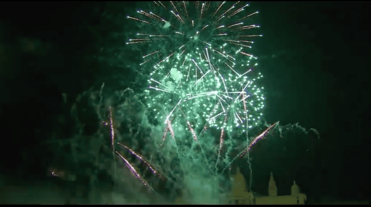 Green fireworks bursting above Avinguda de la Reina Maria Cristina during La Mercè’s Piromusical finale.