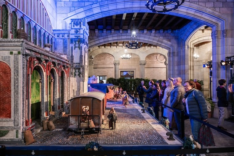 Visitors admiring a detailed live nativity scene (pessebre vivent) in Barcelona, showcasing traditional Catalan Christmas decorations and performances