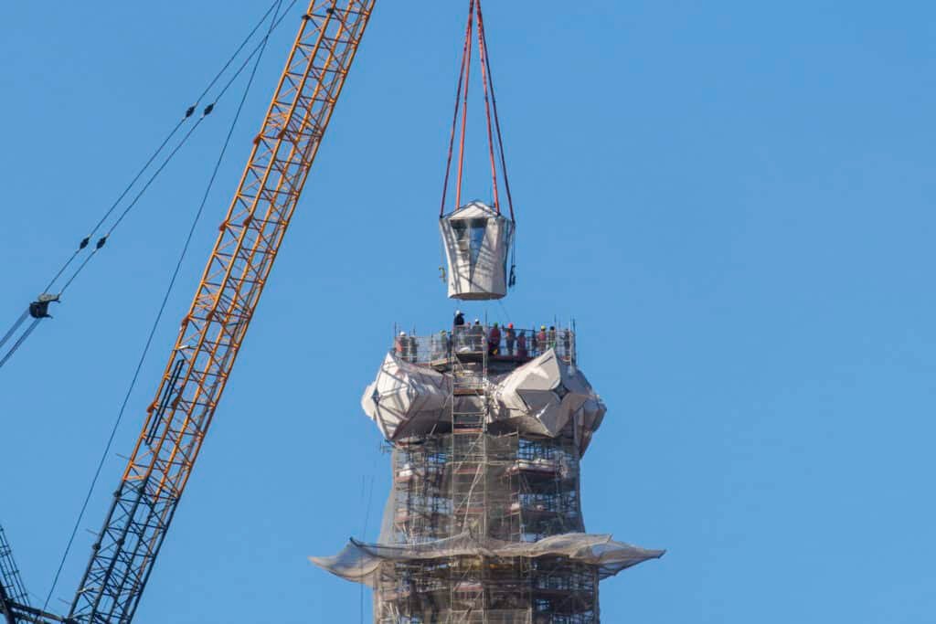 Crane lifting the upper arm of the cross toward the top of the Tower of Jesus Christ at the Sagrada Familia