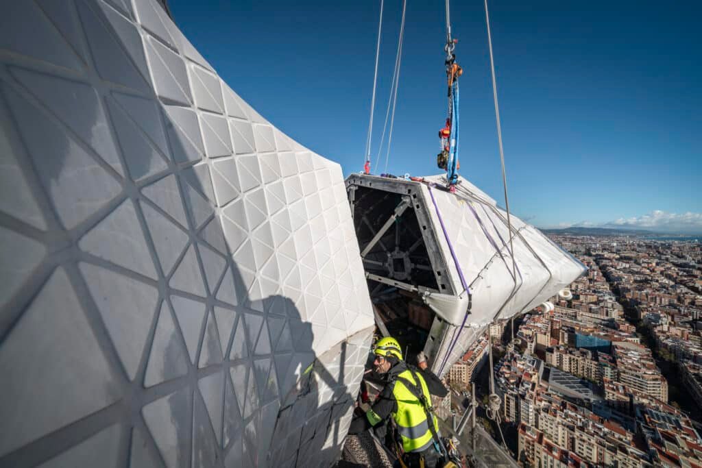 Workers guiding the first horizontal arm of the cross during installation on the Tower of Jesus Christ