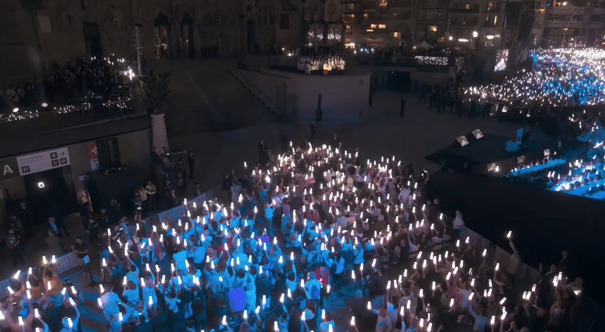 Thousands of attendees holding lights during the centenary celebration of Antoni Gaudí.