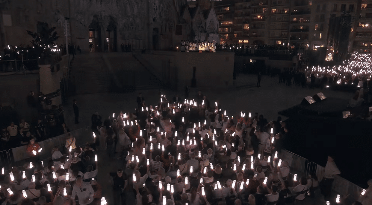 Audience members holding illuminated lights during the centenary celebration of Antoni Gaudí at the Sagrada Familia.