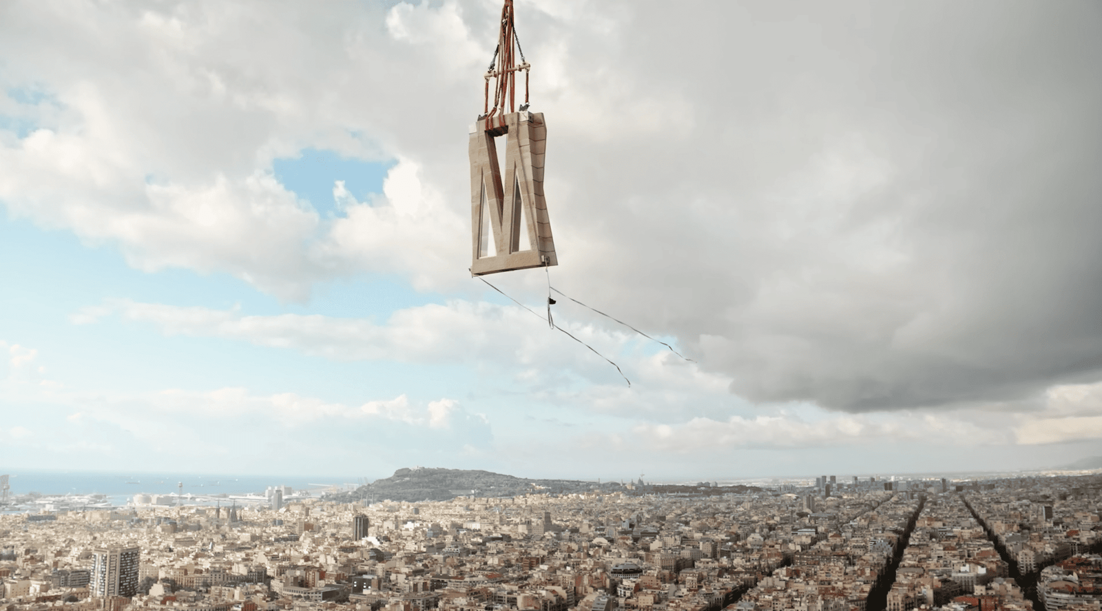 A section of the Jesus Tower cross being lifted by crane high above the city of Barcelona during construction at the Sagrada Família.