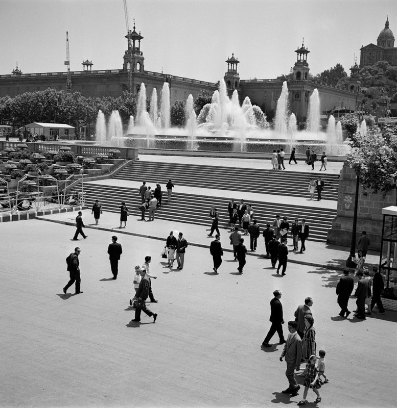 Crowd walking through Montjuïc plaza with the fountain area in the background (historic photo)