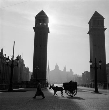Venetian Towers at Montjuïc shown in silhouette with a figure and cart in the foreground