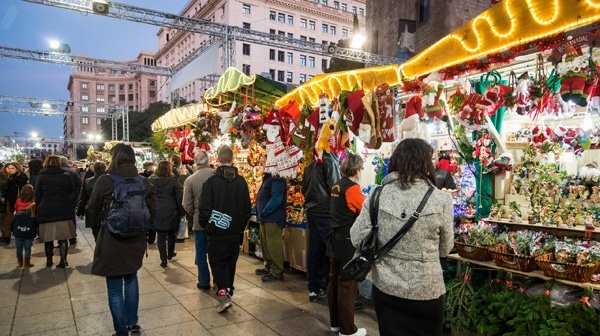 Shoppers at the Fira de Santa Llúcia Christmas market in Barcelona, surrounded by festive stalls and holiday lights