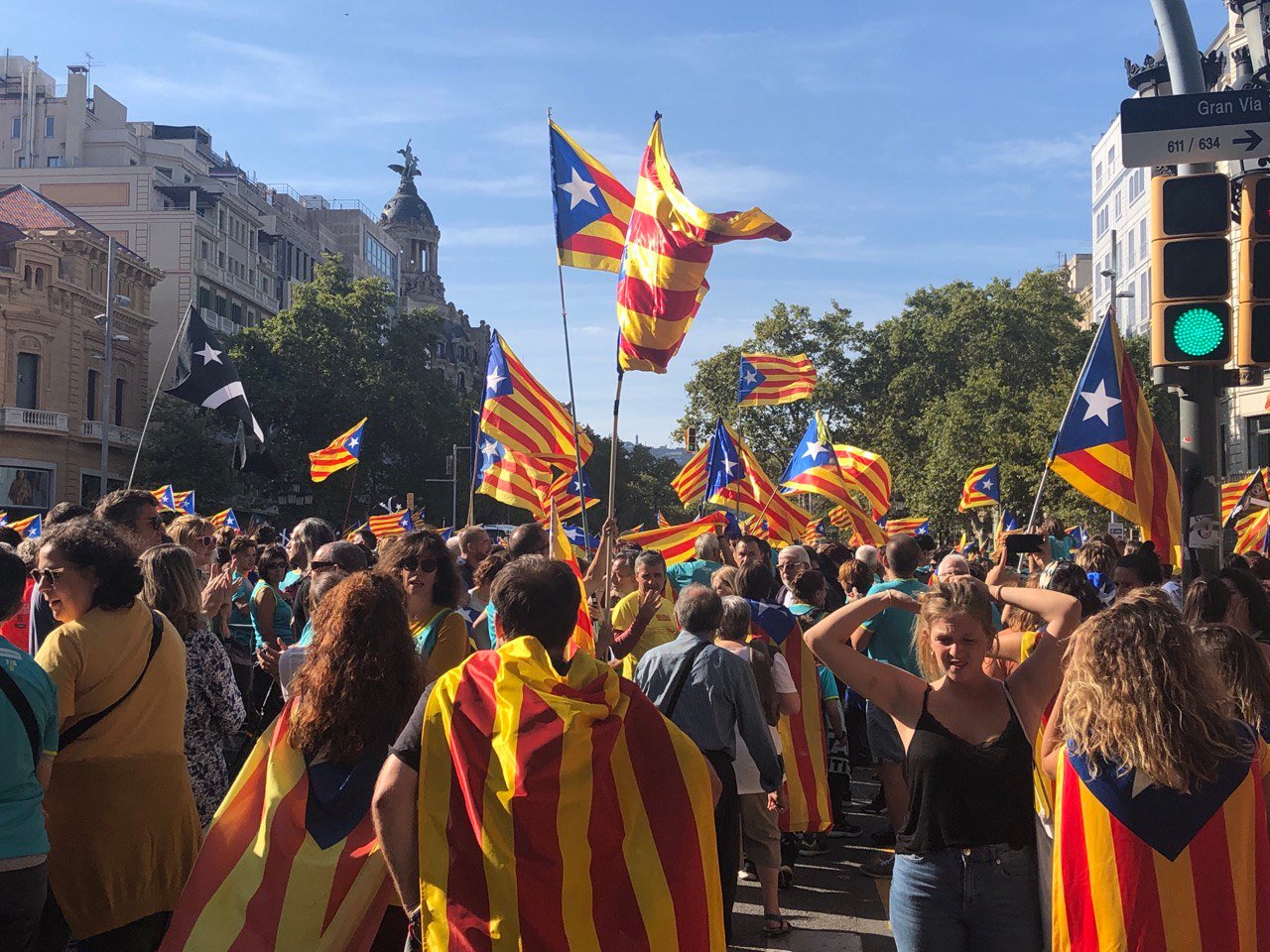 People wearing Catalan flags as capes during La Diada on a Barcelona street.