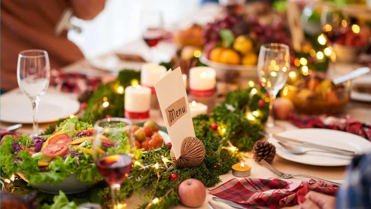 A beautifully set Christmas dinner table with festive decorations, cookies, and soft candlelight.