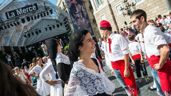 A woman in traditional Catalan dress smiles as she takes part in a cultural parade during La Mercè.