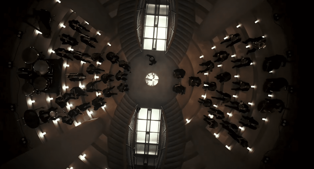 Orchestra arranged beneath the geometric architecture of the Sagrada Familia.