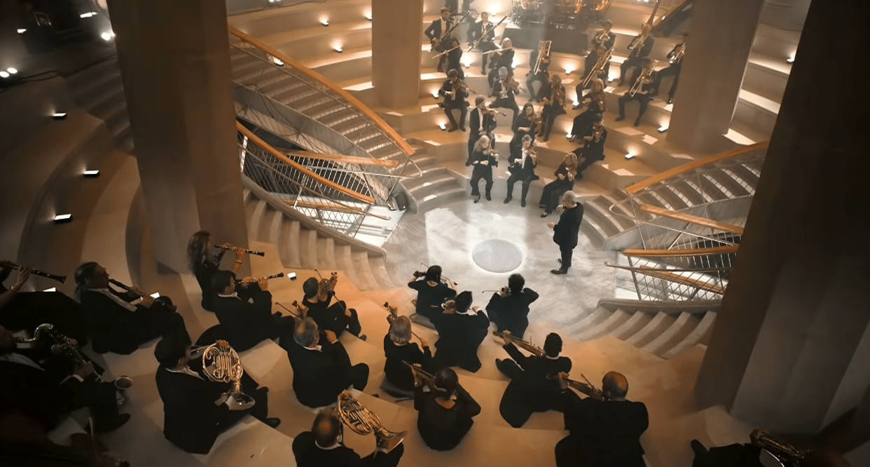 Orchestra performing among the monumental columns of the Sagrada Familia during the Antoni Gaudí centenary tribute.