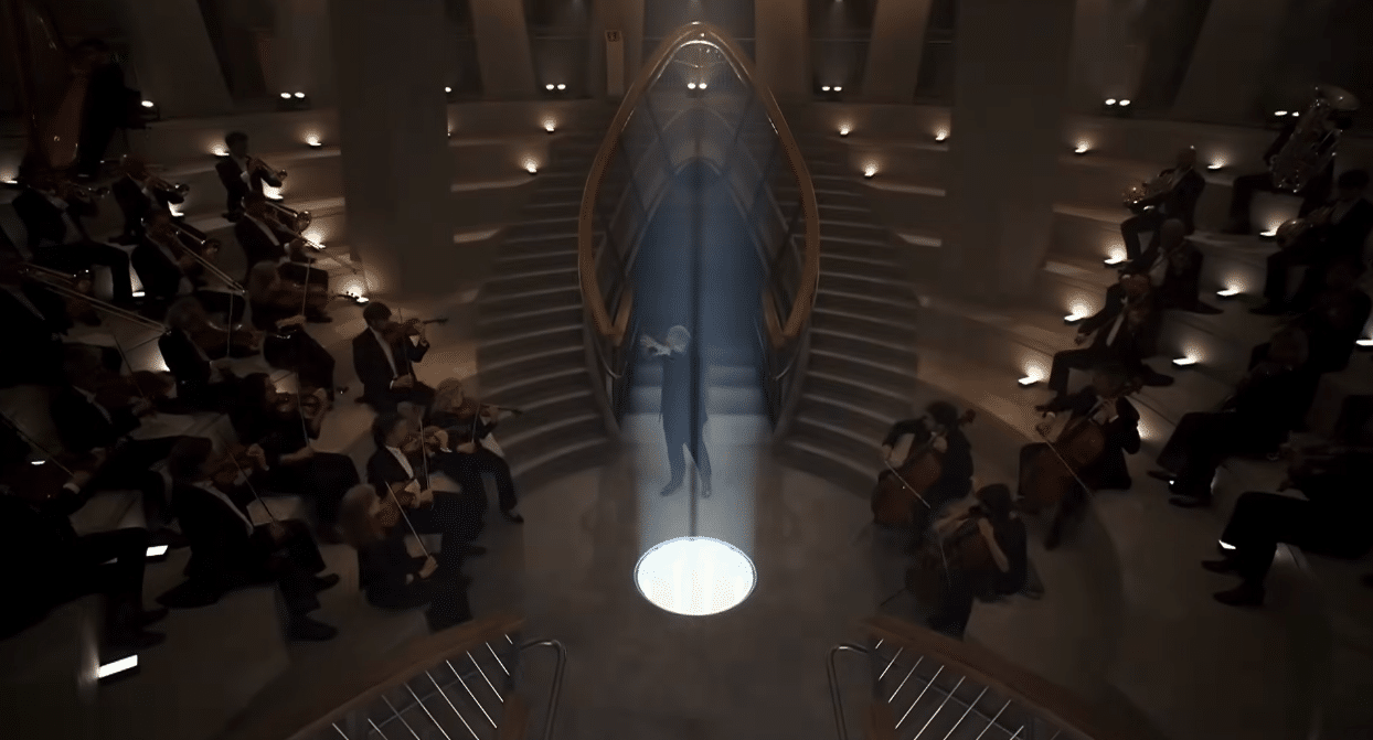 Musicians performing beneath a dramatic beam of light during the centenary tribute to Antoni Gaudí.