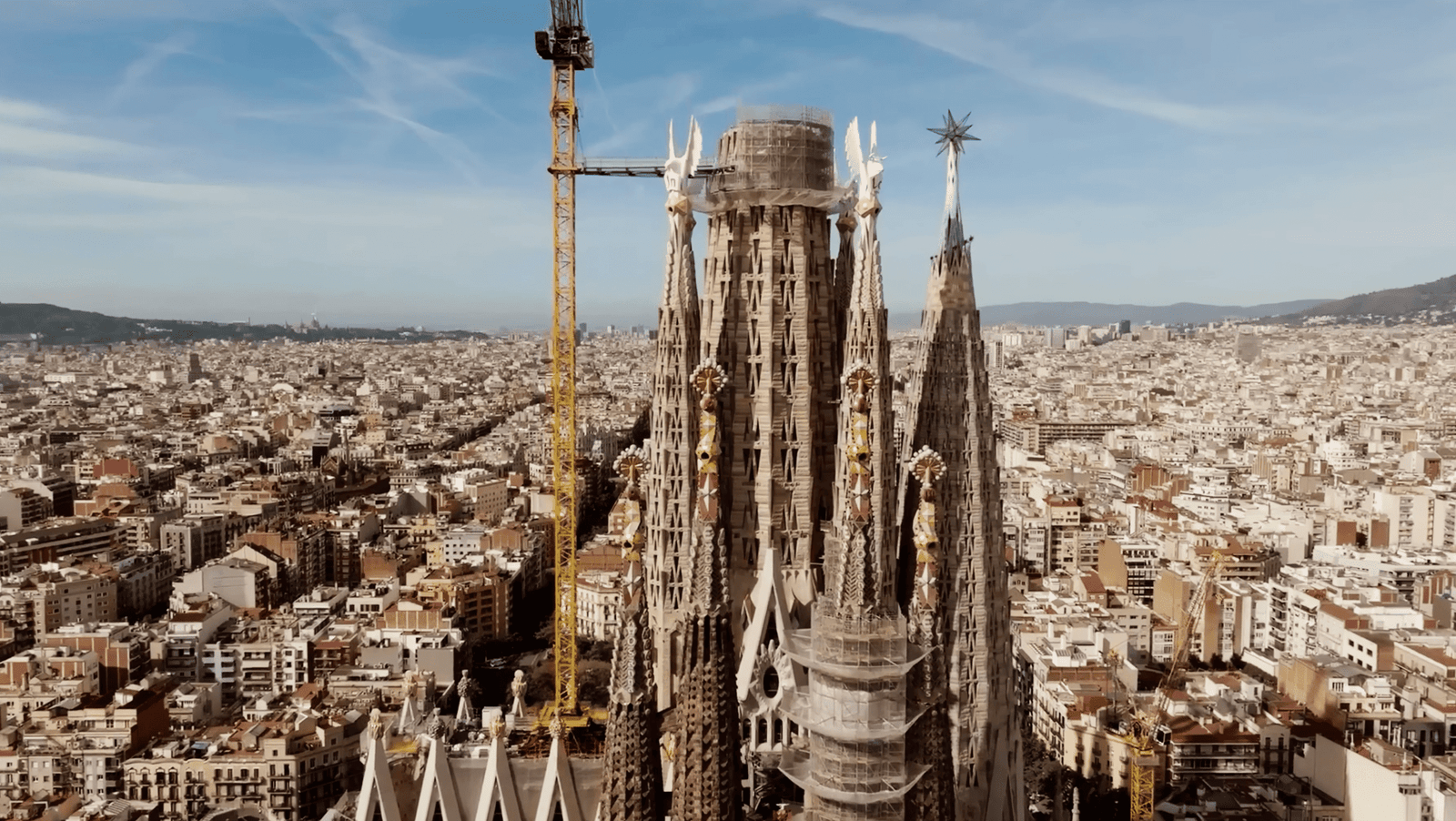 Panoramic view of the Sagrada Família with the Jesus Tower under construction, rising above Barcelona’s skyline.