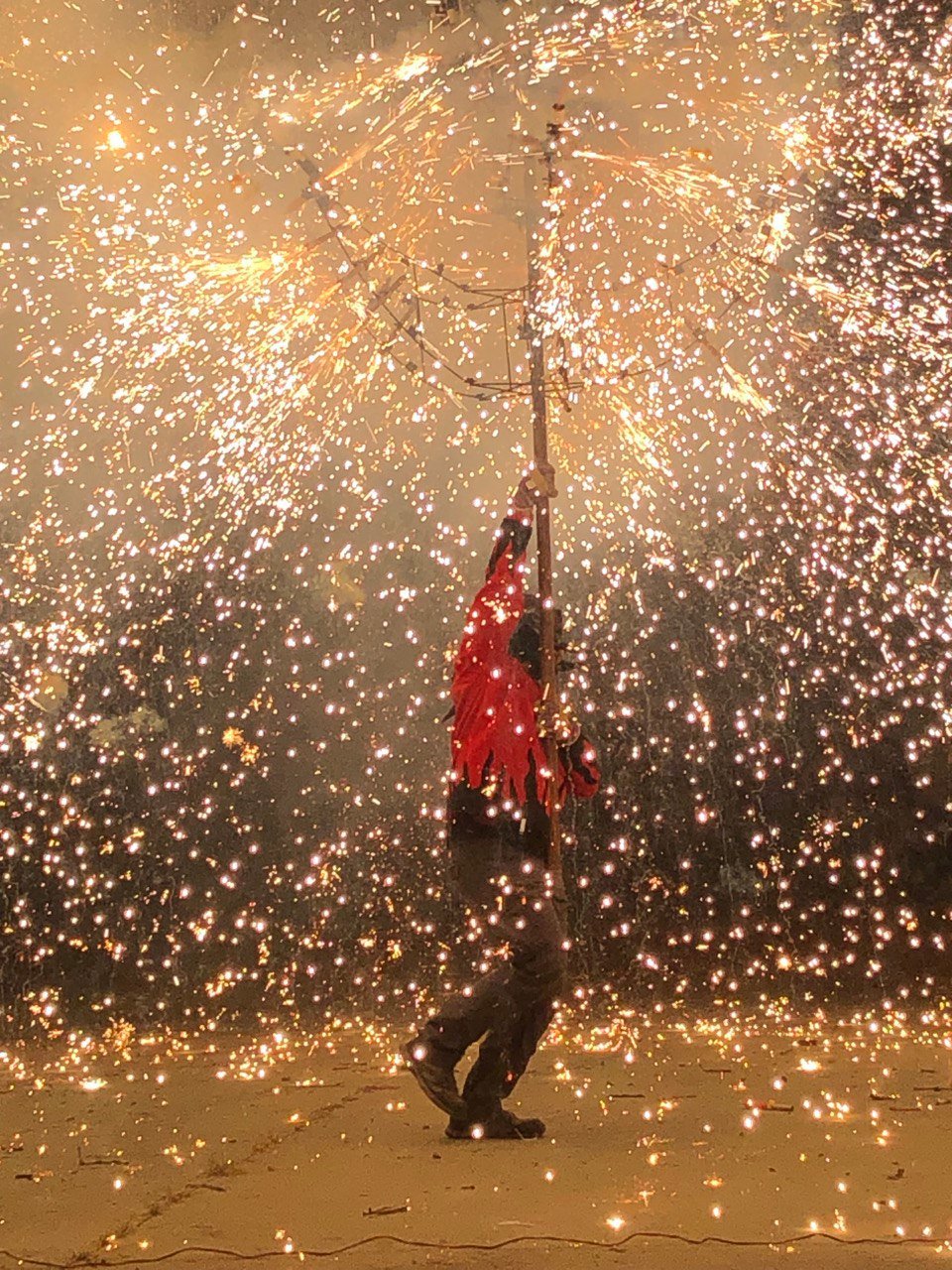 A diable surrounded by a shower of sparks from a spinning firework structure during the Sant Joan fire rituals in Barcelona
