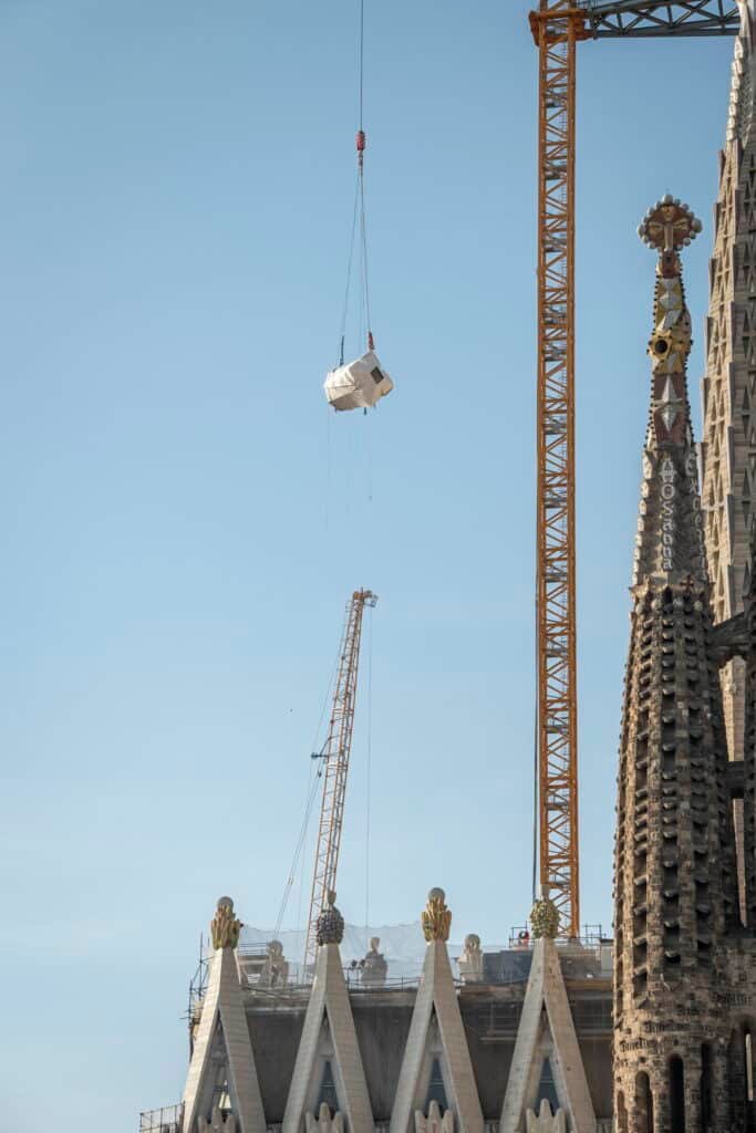 Fourth horizontal cross arm suspended by crane above the Sagrada Familia during installation on the Tower of Jesus Christ
