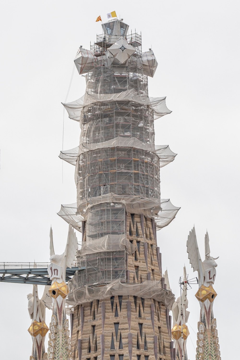 Cross of the Tower of Jesus Christ at the Sagrada Familia with the Catalan and Vatican flags