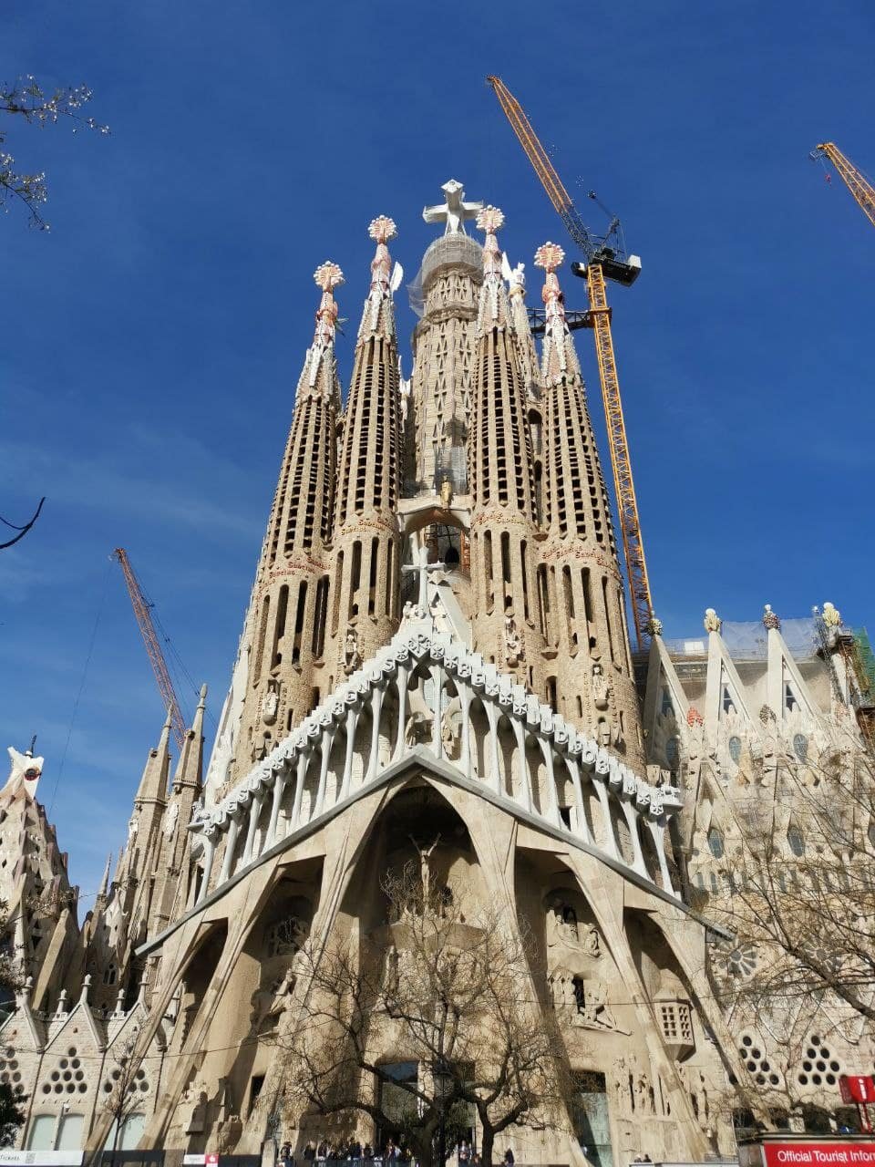 Front view of the Sagrada Família in Barcelona with the completed cross atop the Tower of Jesus Christ.